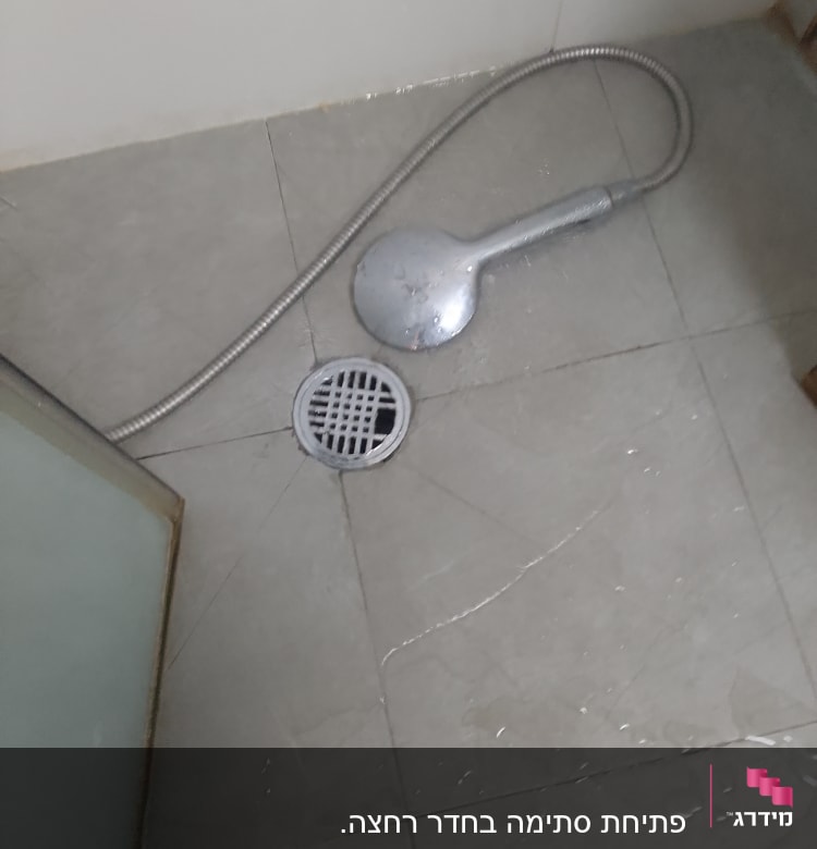 ראש מקלחת וצינור על רצפת מקלחת רטובה